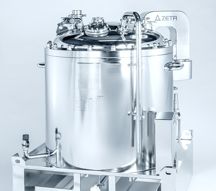 The image shows a shiny metal tank with pipes, valves, and gauges attached to the top. It’s mounted on a frame and labeled “ZETA.”