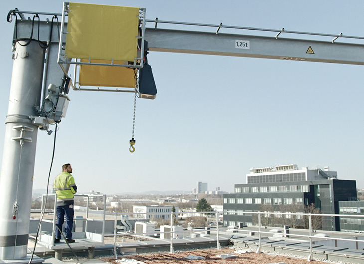 The image shows a rooftop construction site with a person standing near a crane labeled 