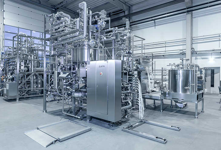 Large production skids made of stainless steel in fabrication hall, including vessels and complicated piping and wiring