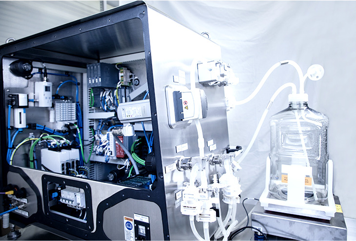 Mobile skid for gene therapy production, showing an open EIC cabinet and a bottle connected with several hoses